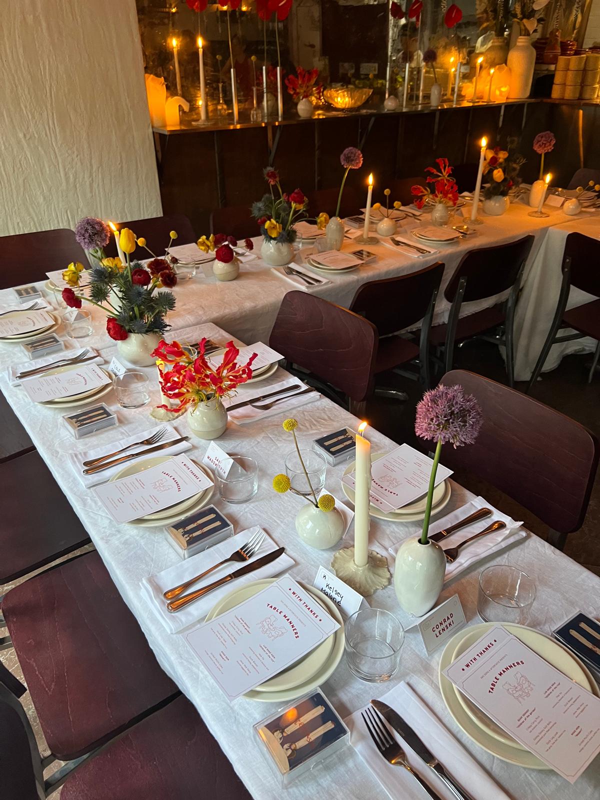 Candlelit private dining table laid with menus, name cards, and taper candles